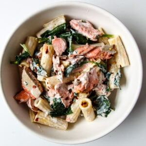 Salmon & spinach pasta in a white bowl.