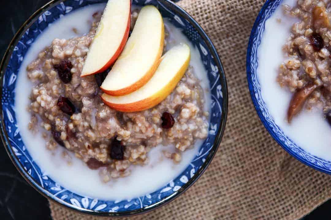A bowl of oatmeal, with apple slices
