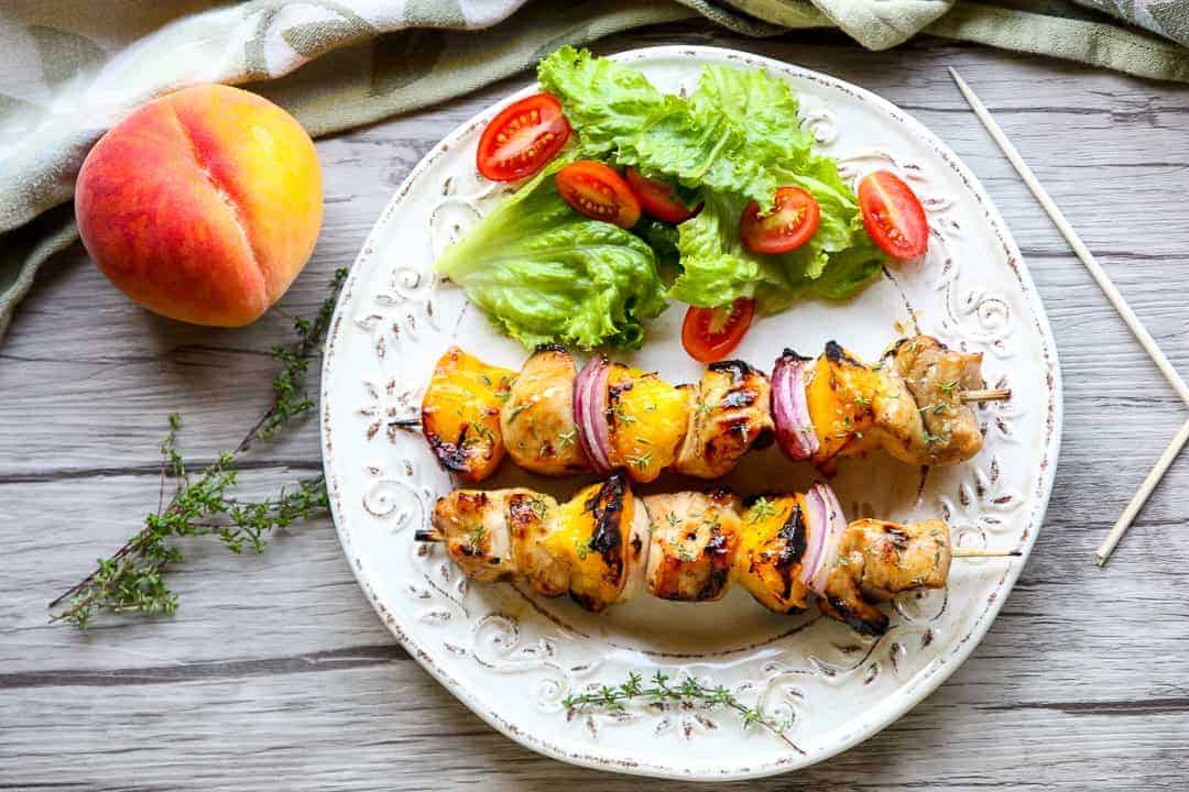 A plate of food on a table, with chicken kebabs and salad