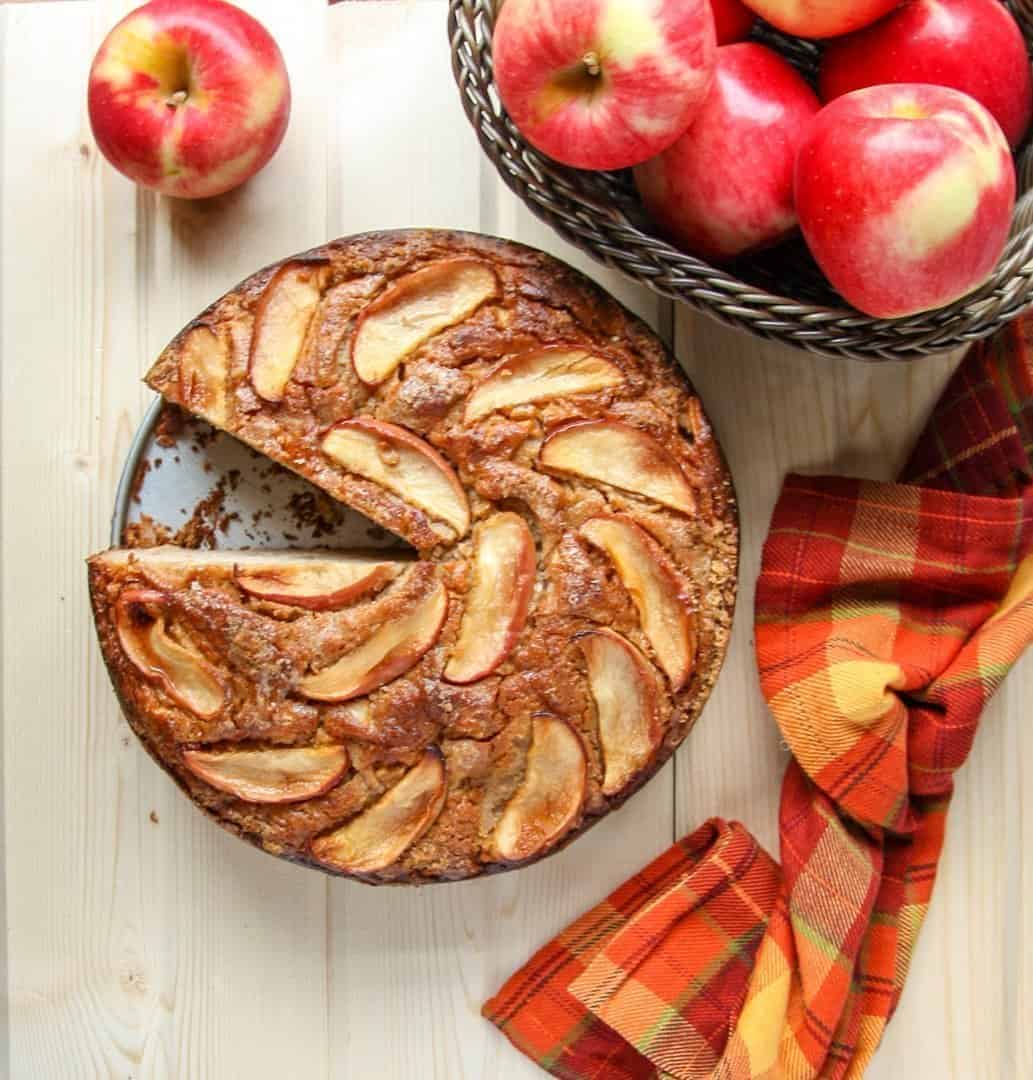 A bowl of apples sitting on a table, with a Cake