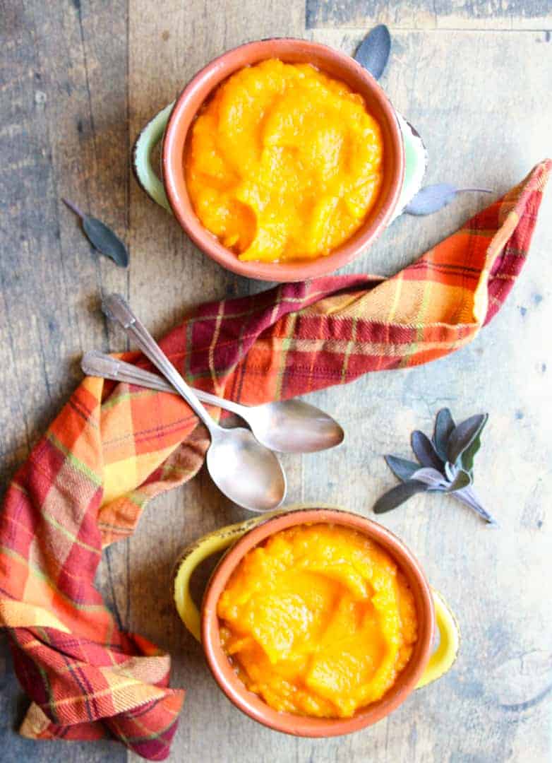 2 bowls of mashed butternut squash with two spoons and a plaid napkin