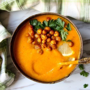 Sweet potato soup in a coconut shell bowl, topped with roasted chickpeas and parsley