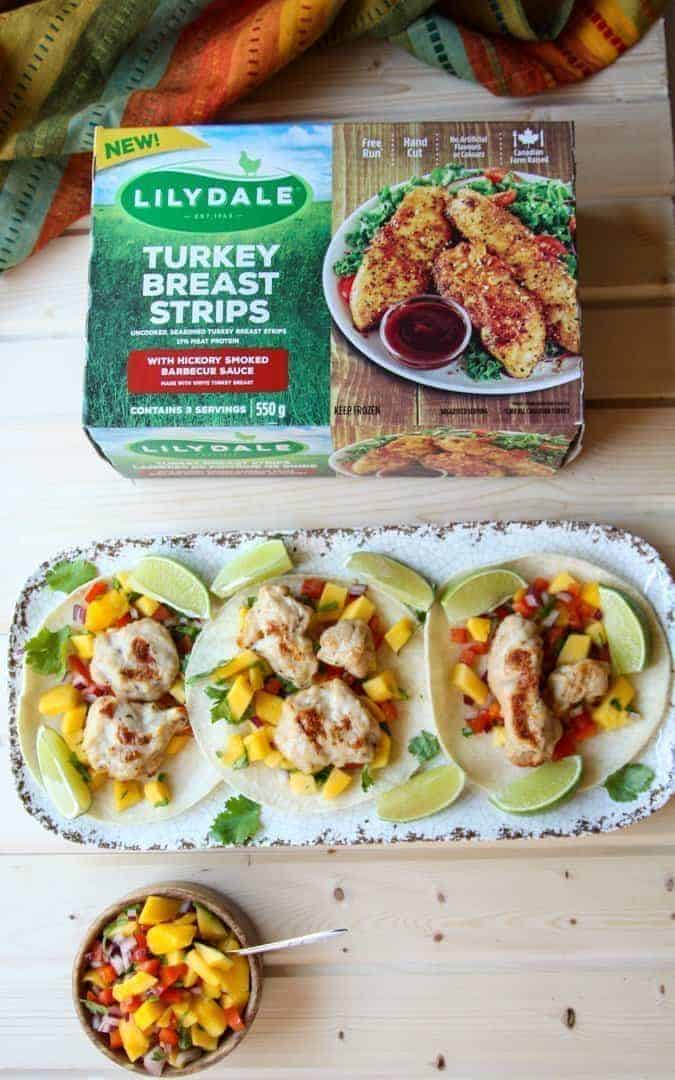 A platter of tacos on a table with a box of frozen turkey strips