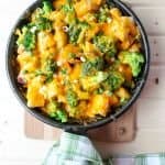 Cheese, broccoli, and potato casserole in black skillet.