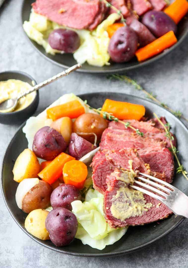 A round black plate of vegetables and sliced meat,