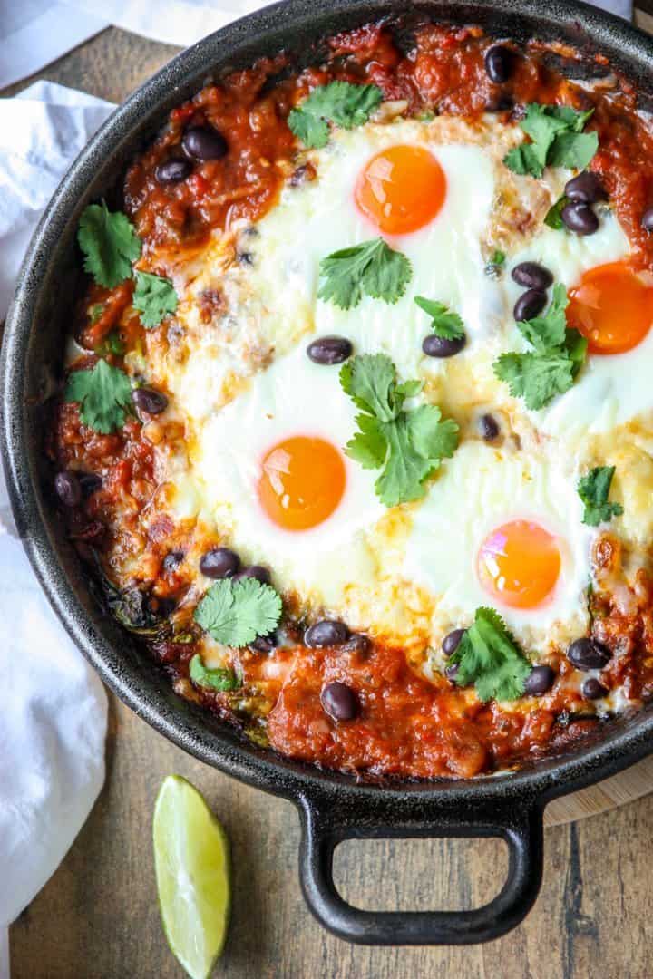 Top shot of a black skillet filled with baked huevos rancheros.