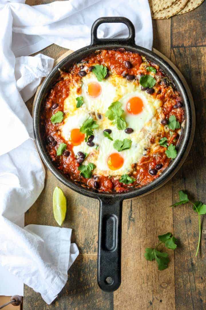 Top shot of a black skillet filled with baked huevos rancheros.