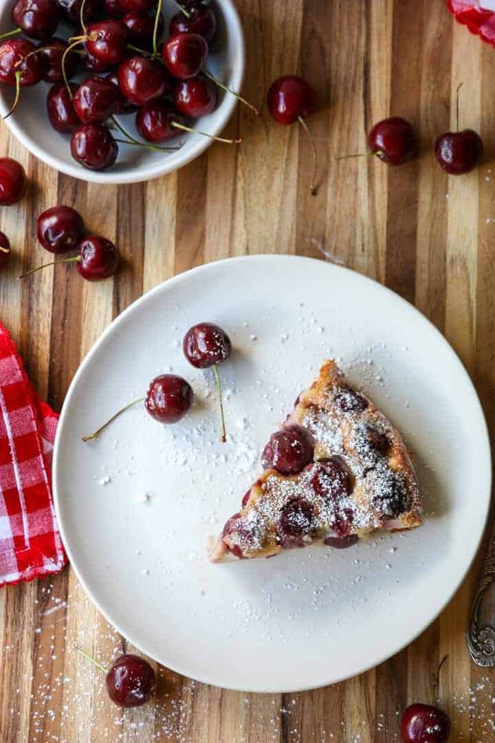 slice of fruit dessert in baking dish on white plate sprinkled with powdered sugar