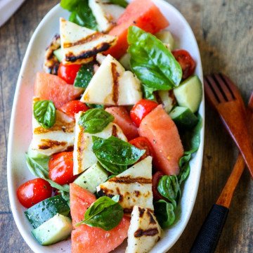 Grilled Halloumi & Watermelon Salad with tomatoes, cucumber & basil on a white platter