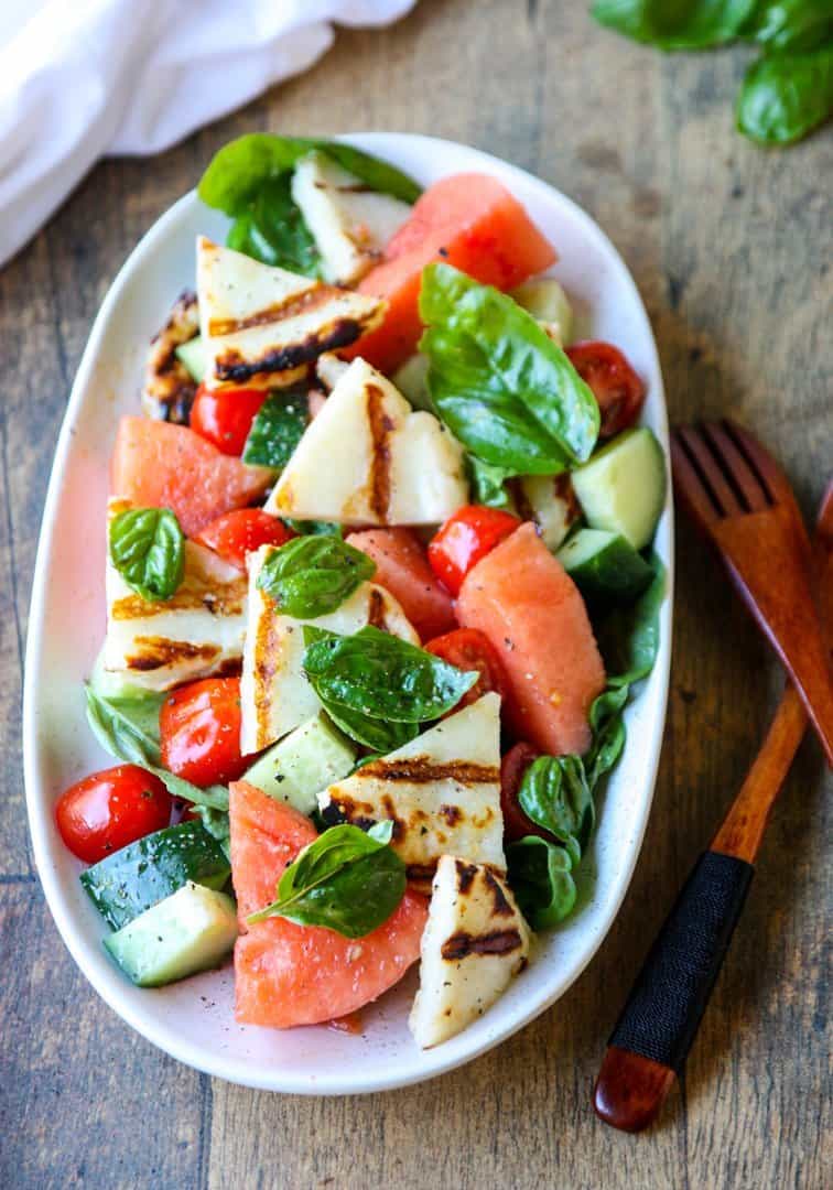 Grilled Halloumi & Watermelon Salad with tomatoes, cucumber & basil on a white platter