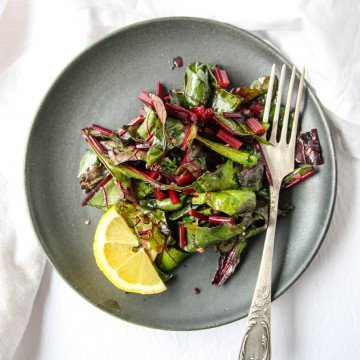 Sautéed Beet Greens on a black plate with a fork