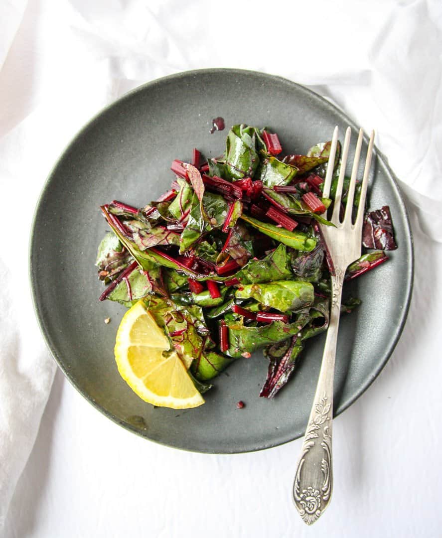 Sautéed Beet Greens on a black plate with a fork