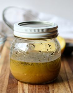 Salad dressing in a glass jar on a wooden board.