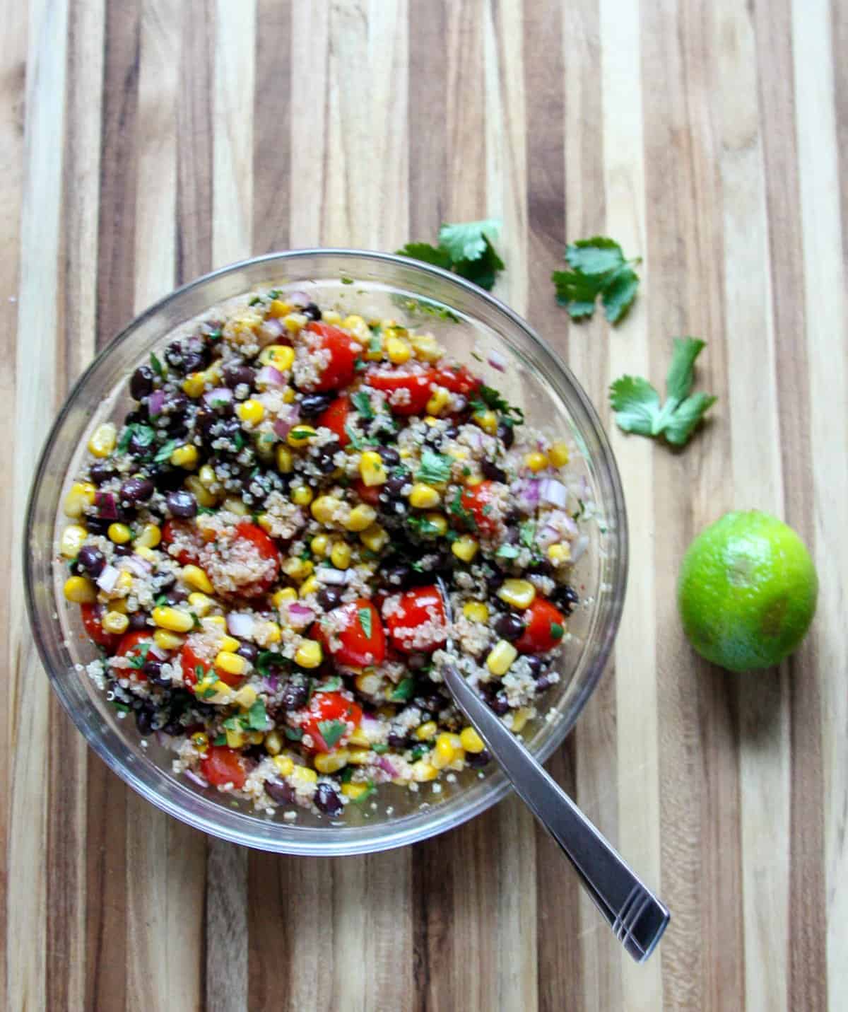 Salad dressing being stirred into salad ingredients in a glass bowl.