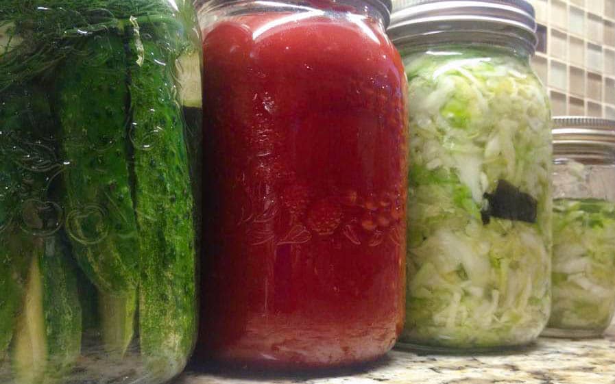 close up of three jars: homemade pickles, jam and sauerkraut