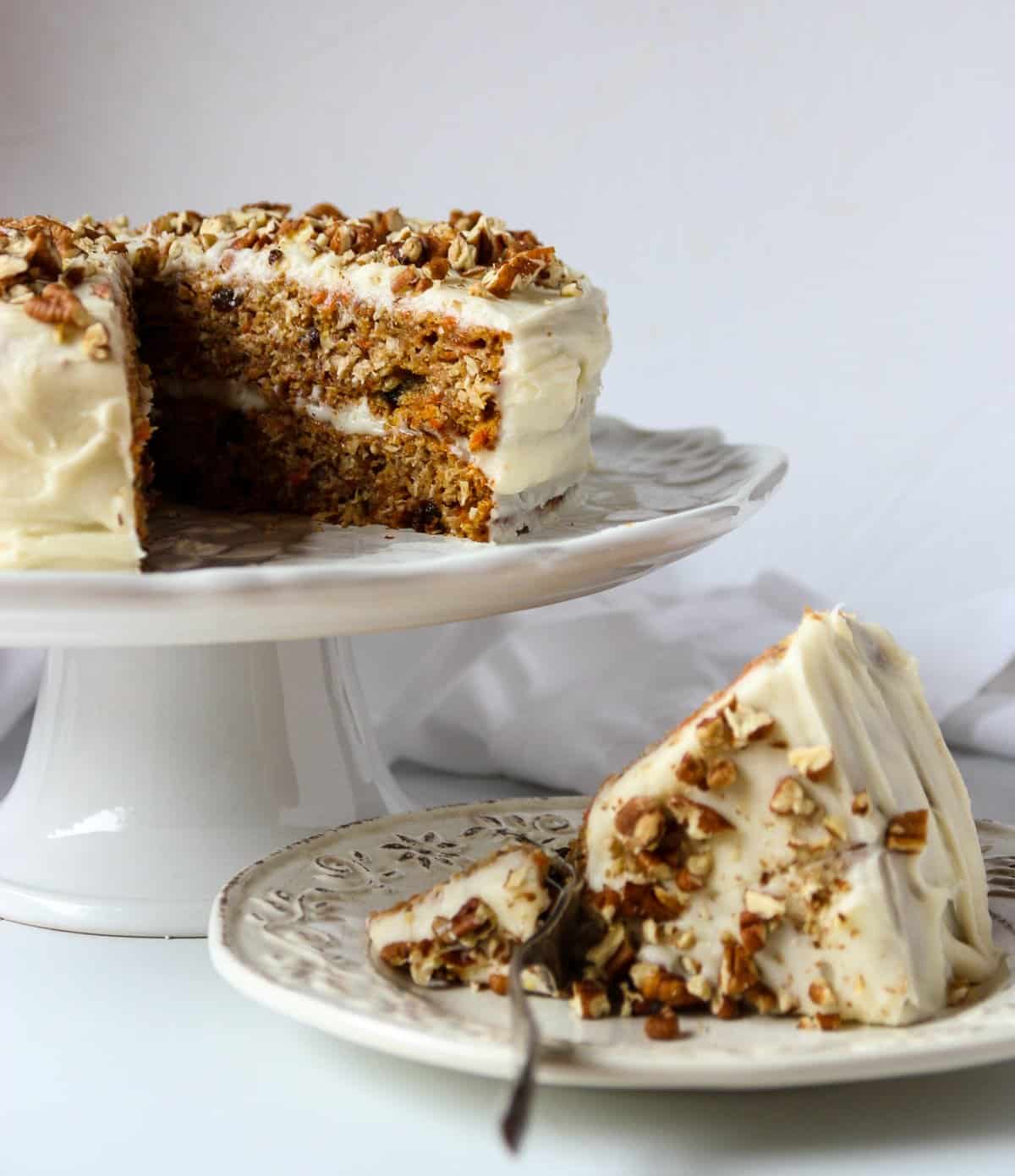 A slice of gluten-free carrot cake on a white plate with a fork.