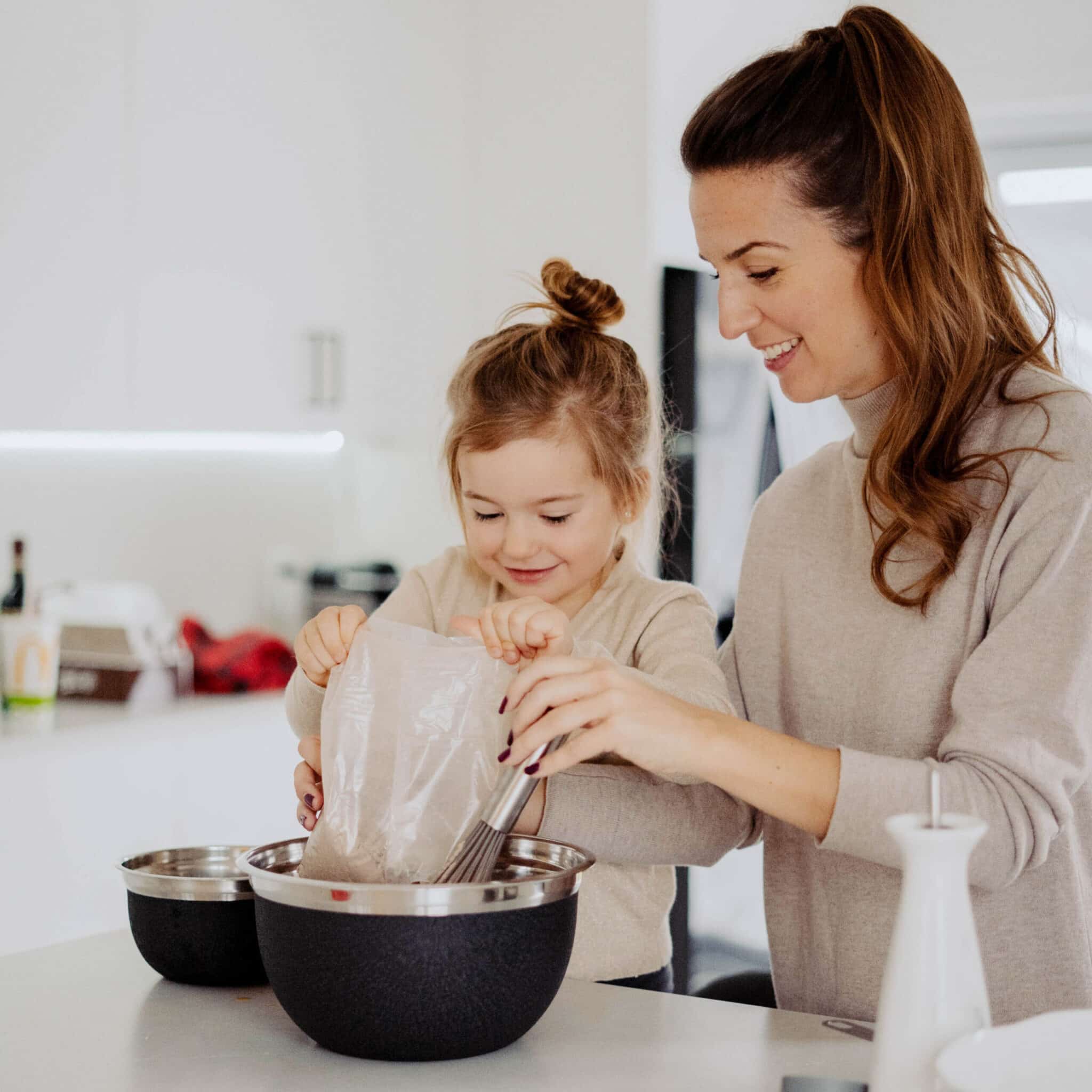 Young mom and daughter making cupcakes in a white kitchen