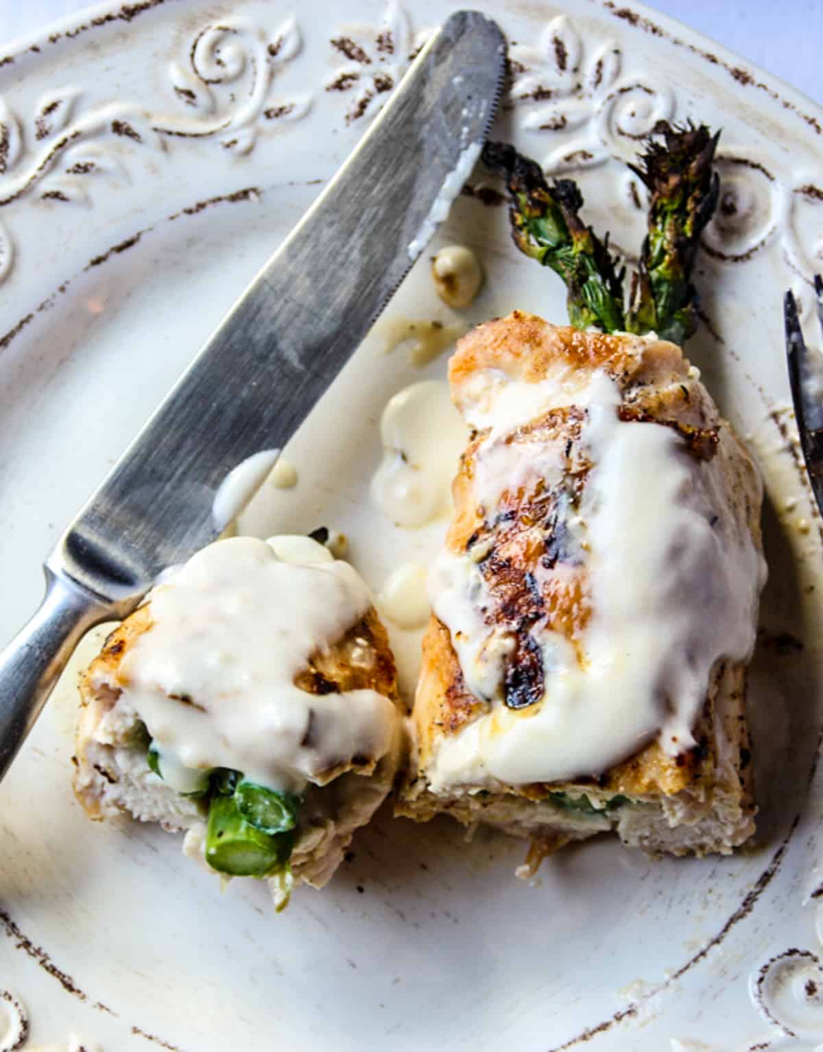 Grilled chicken and asparagus on a white plate.