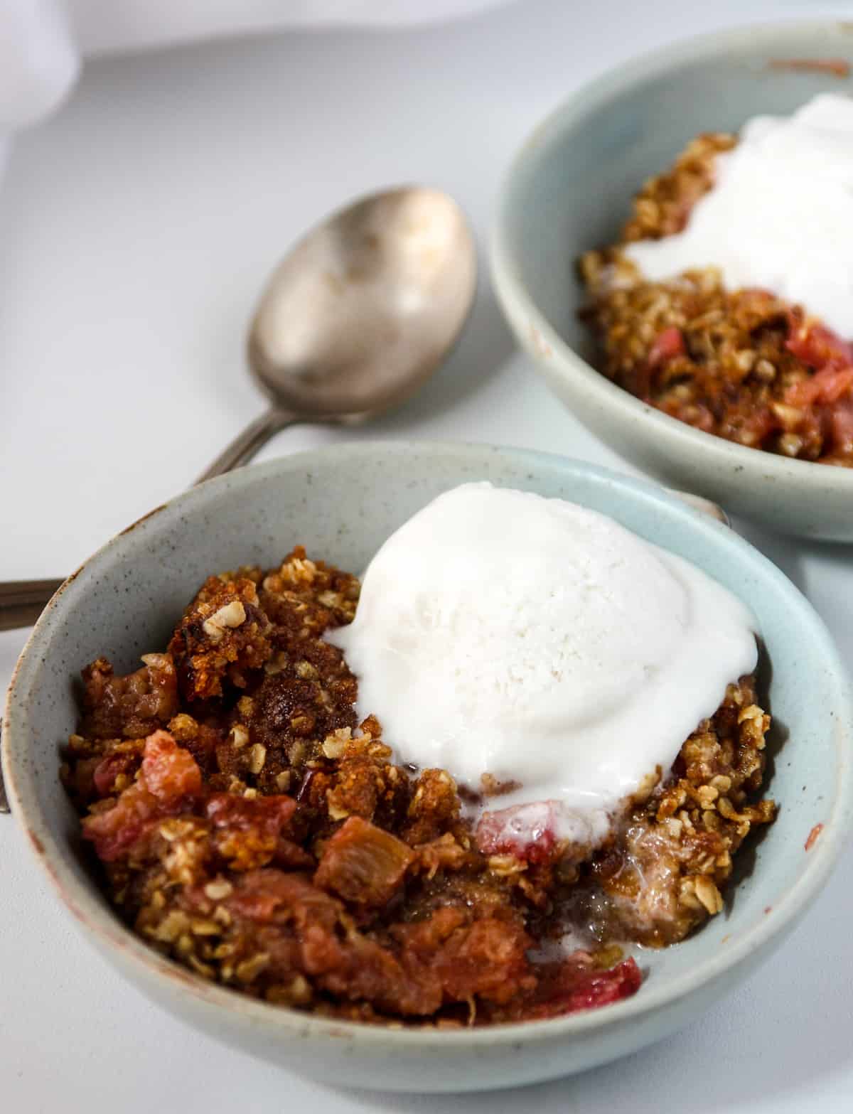 Gluten Free Rhubarb Crisp in a blue bowl topped with a scoop of ice cream.