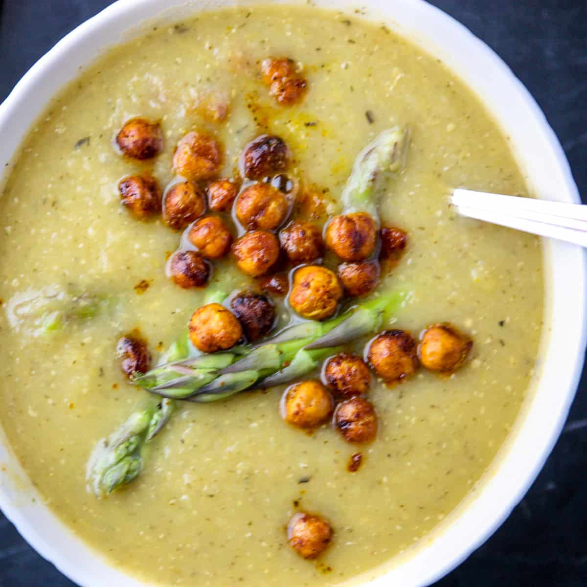 A bowl of vegan asparagus soup garnished with roasted chickpeas.