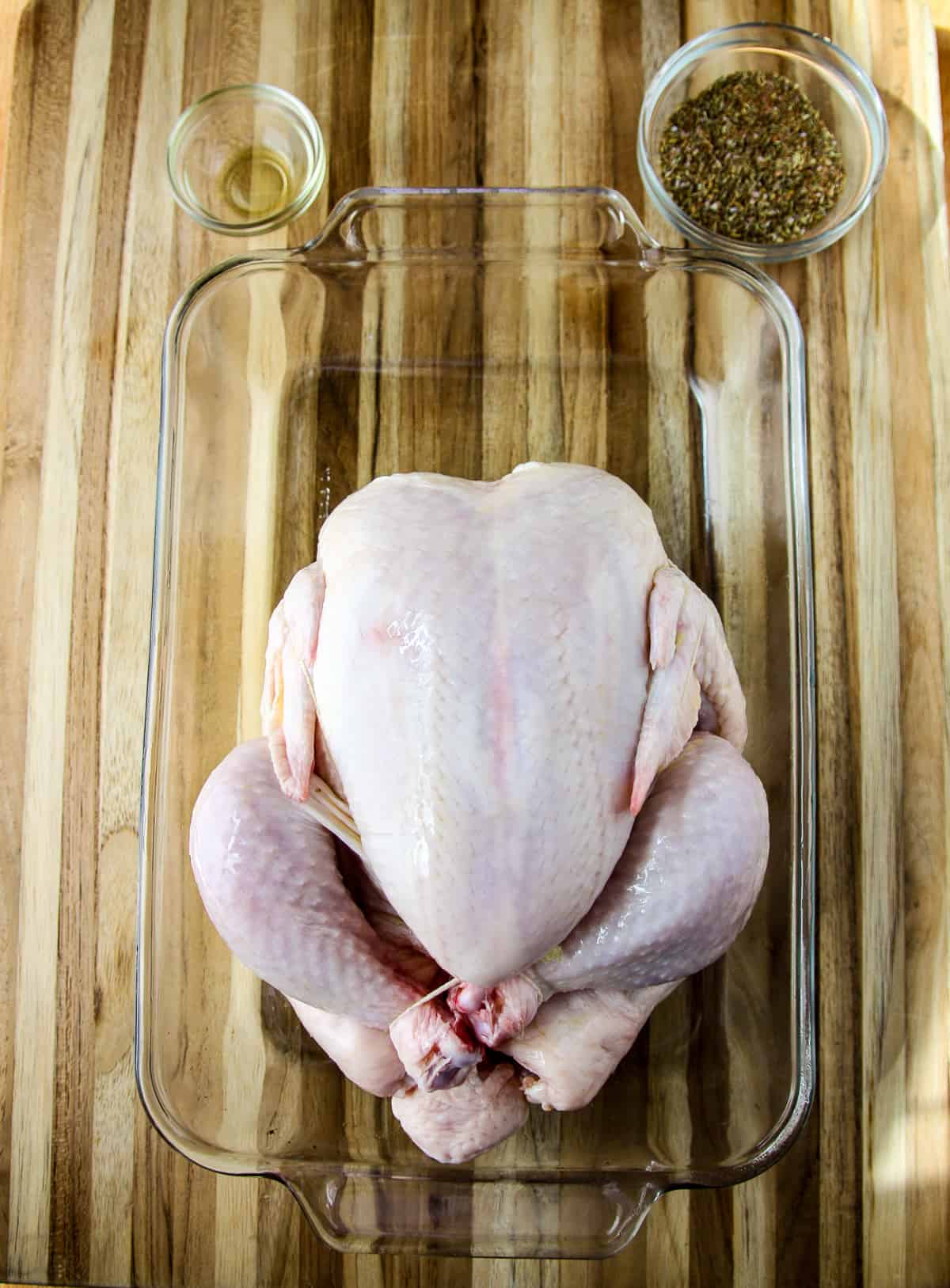 The uncooked whole chicken rubbed with olive oil.