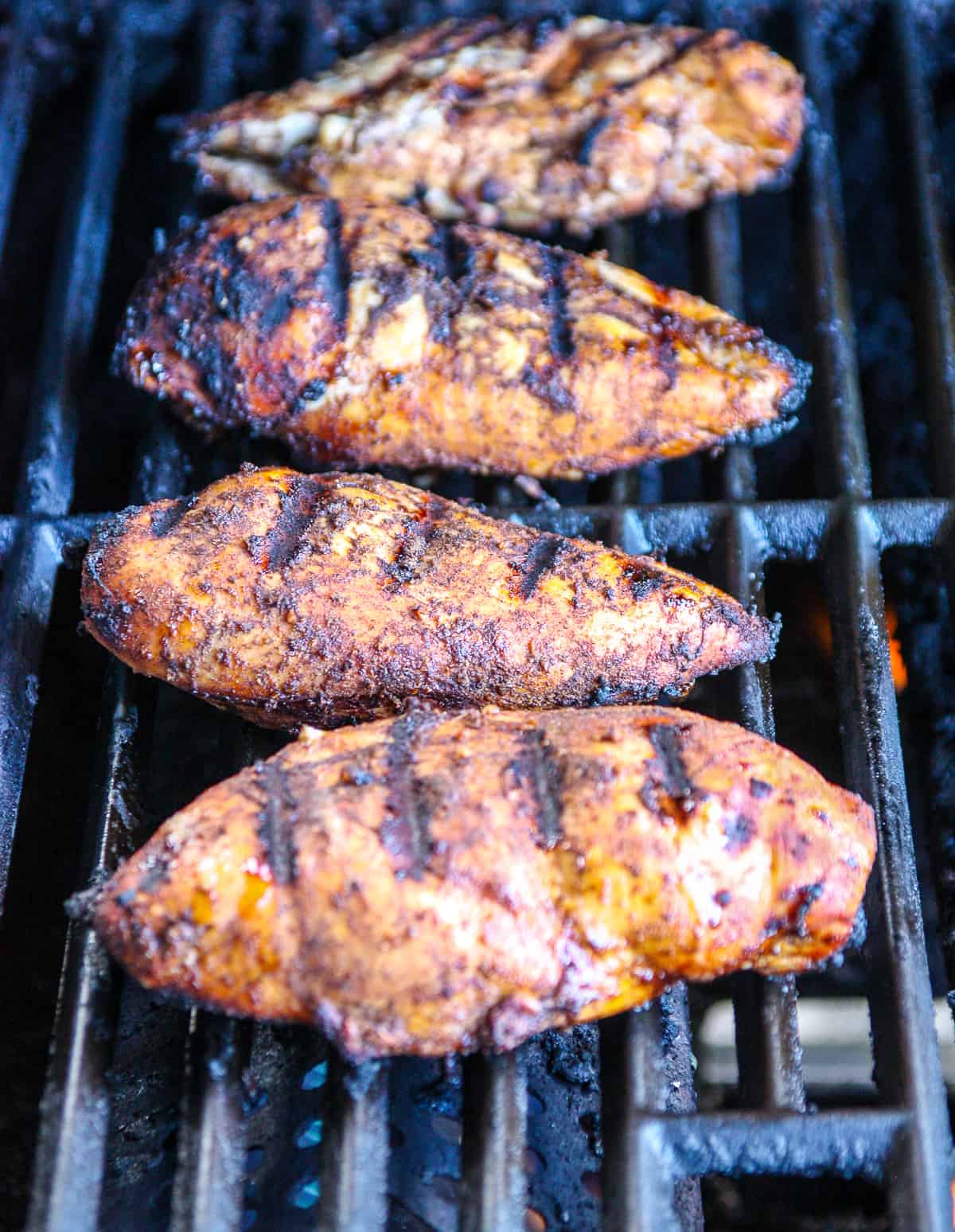 Chicken breasts cooking on a gas grill.