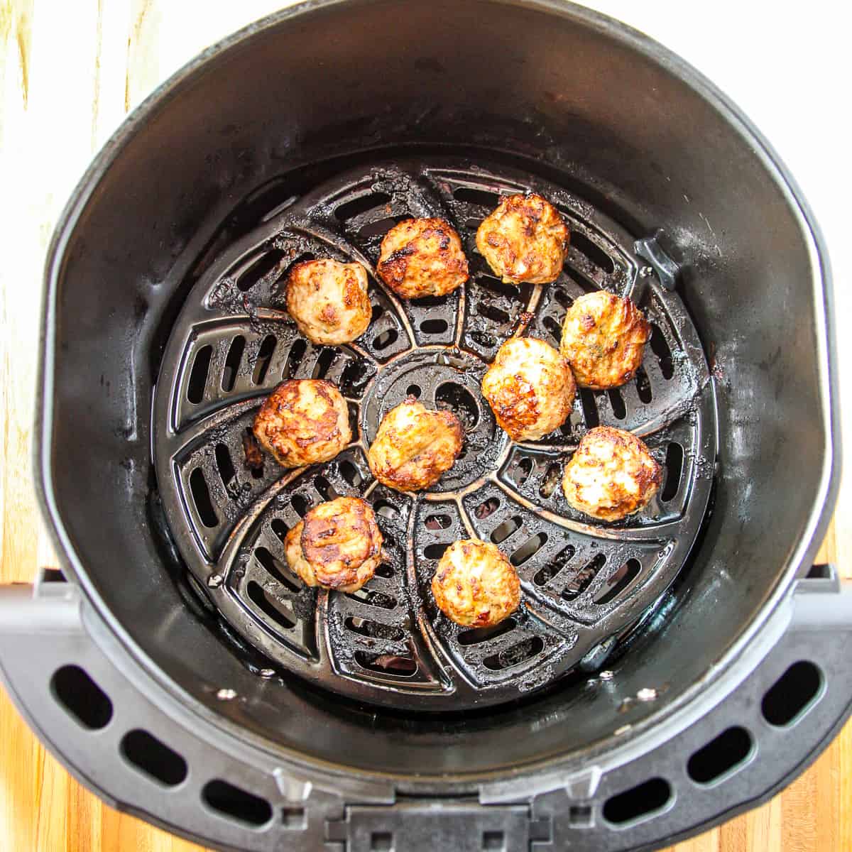 An air fryer basket with cooked turkey meatballs.