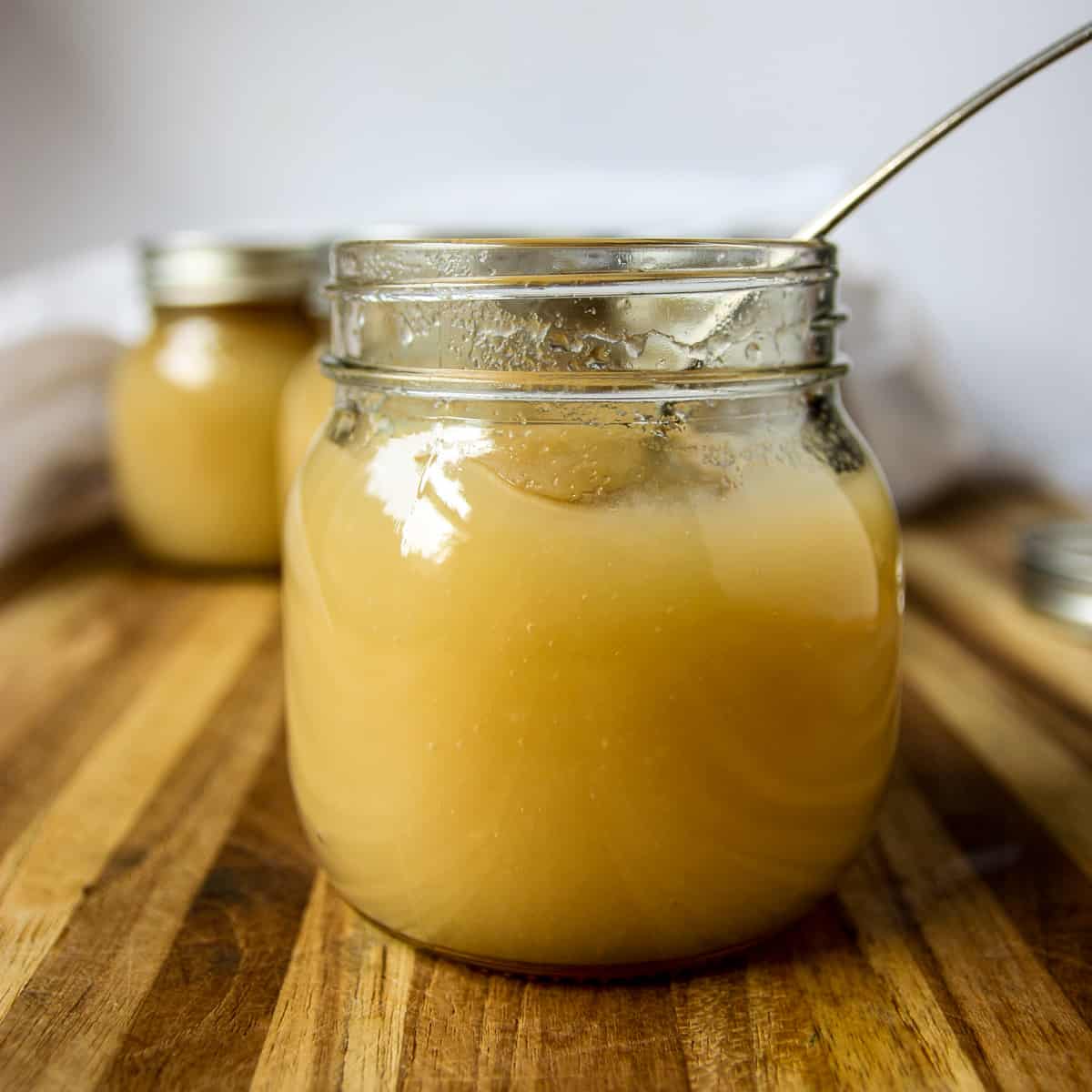 A jar of applesauce with a spoon inserted.