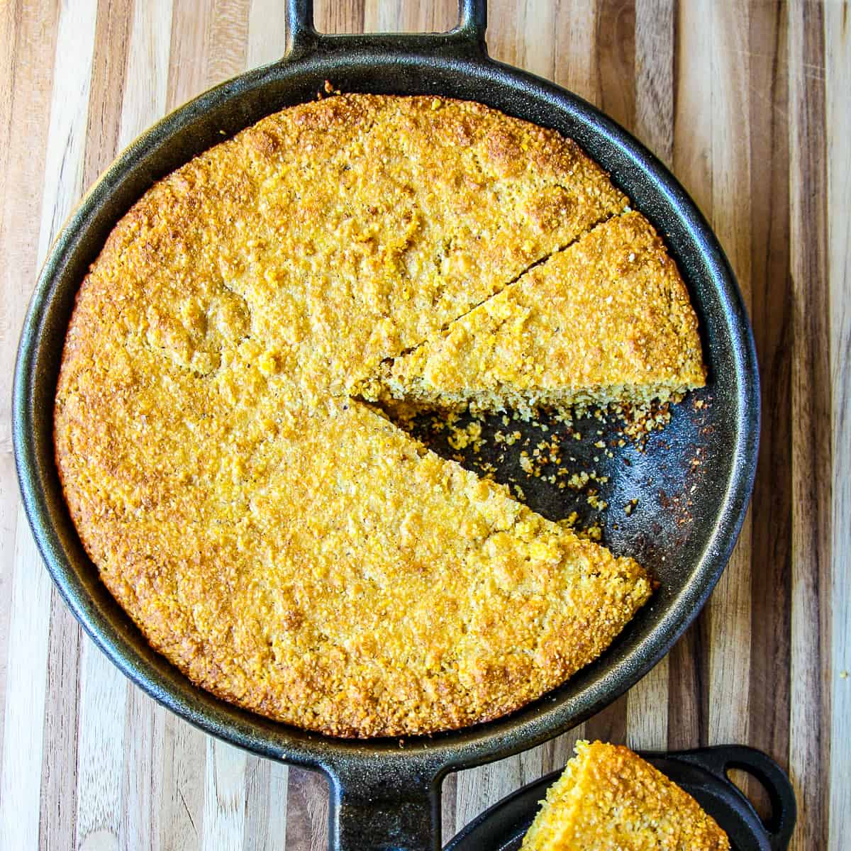 Gluten free cornbread in a cast iron skillet with a slice removed.