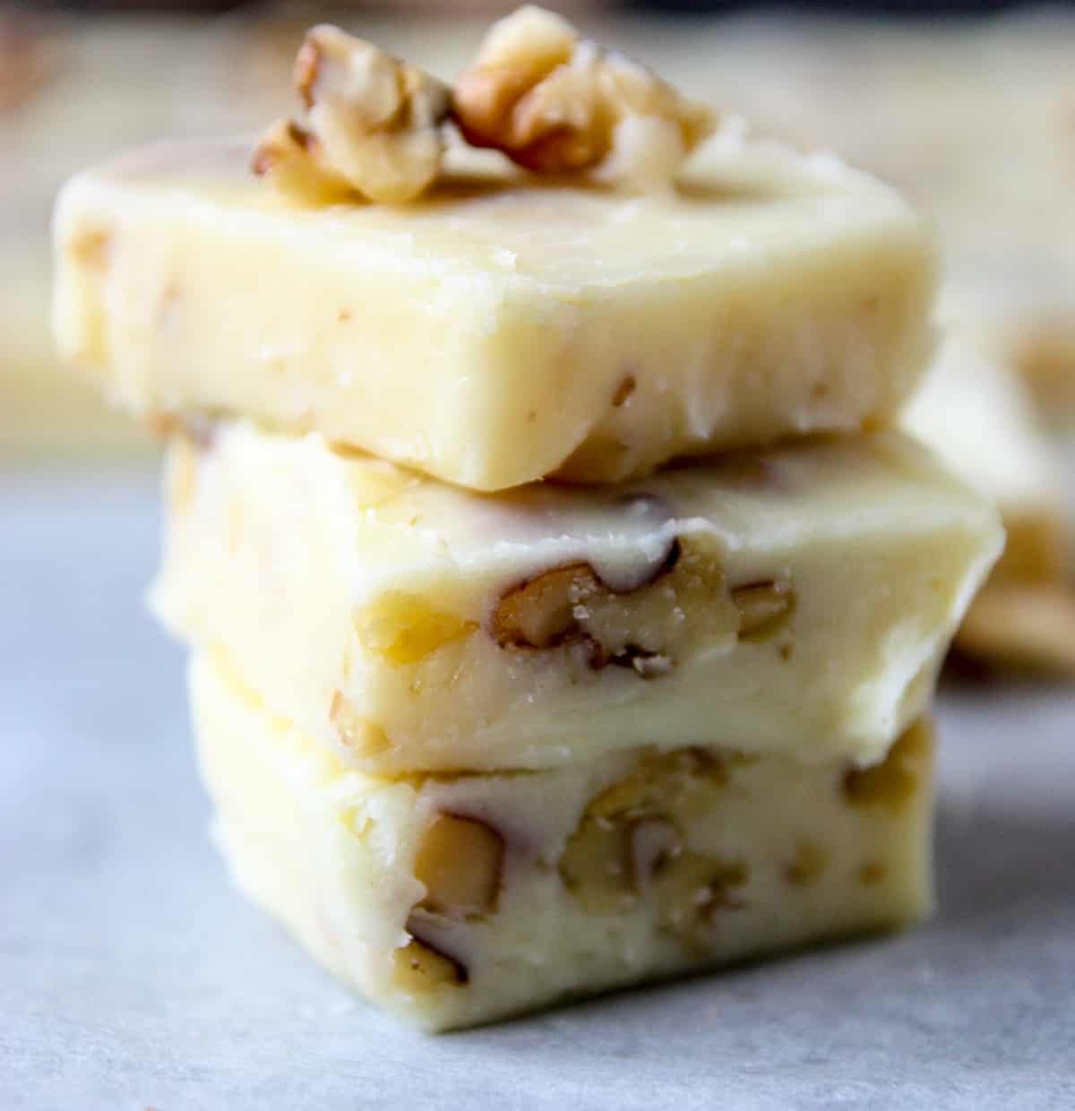 Three pieces of maple walnut fudge stacked on top of each other.