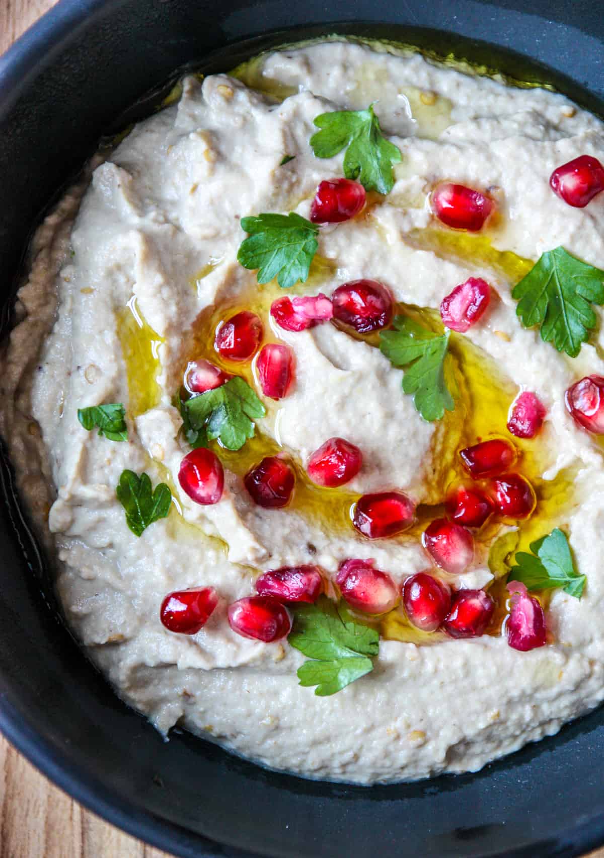 A close up of mutabbal eggplant dip topped with garnish.