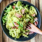 Shredded brussels spouts and bacon in a black bowl.