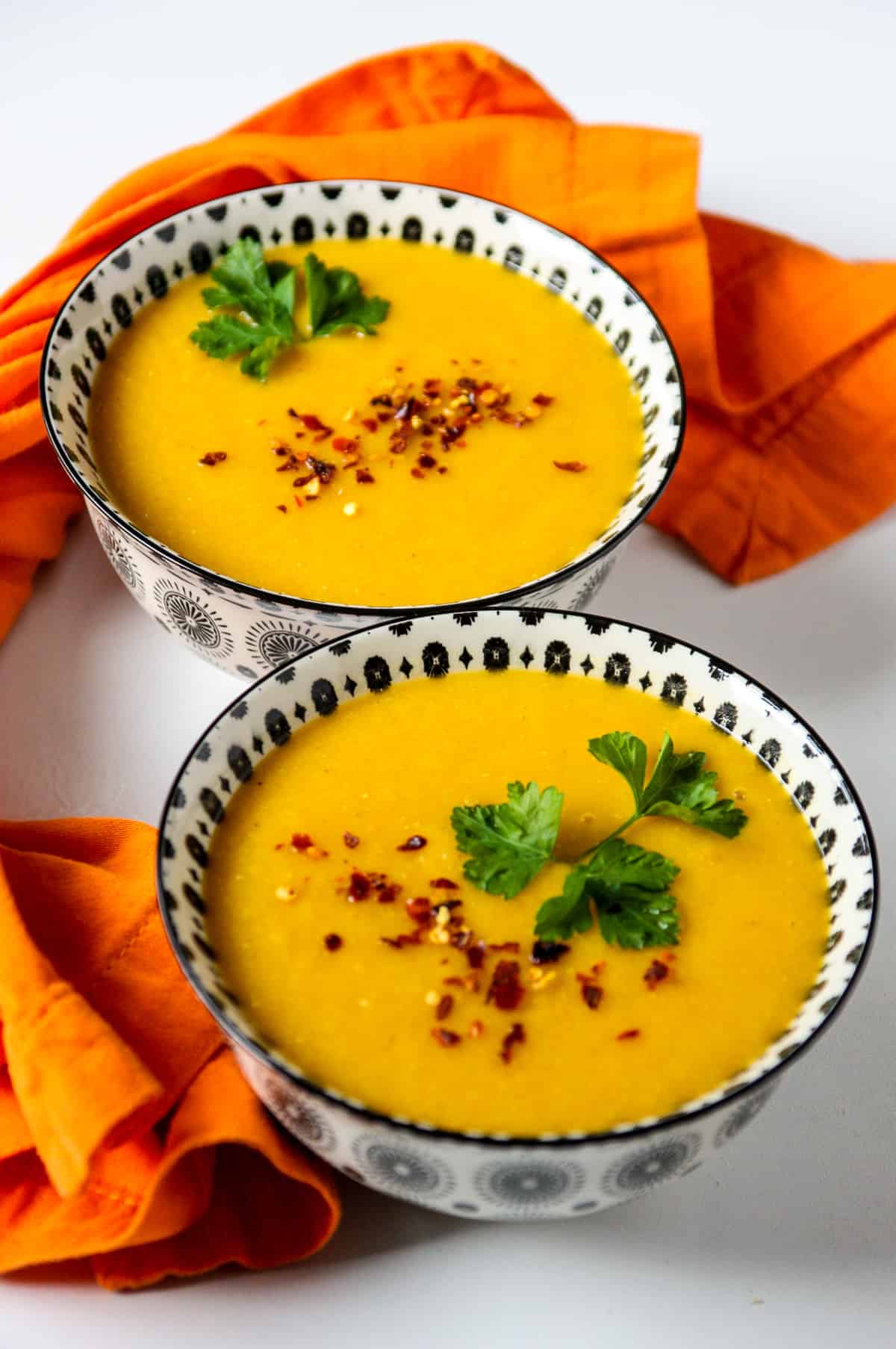Carrot and lentil soup in two black and white bowls.