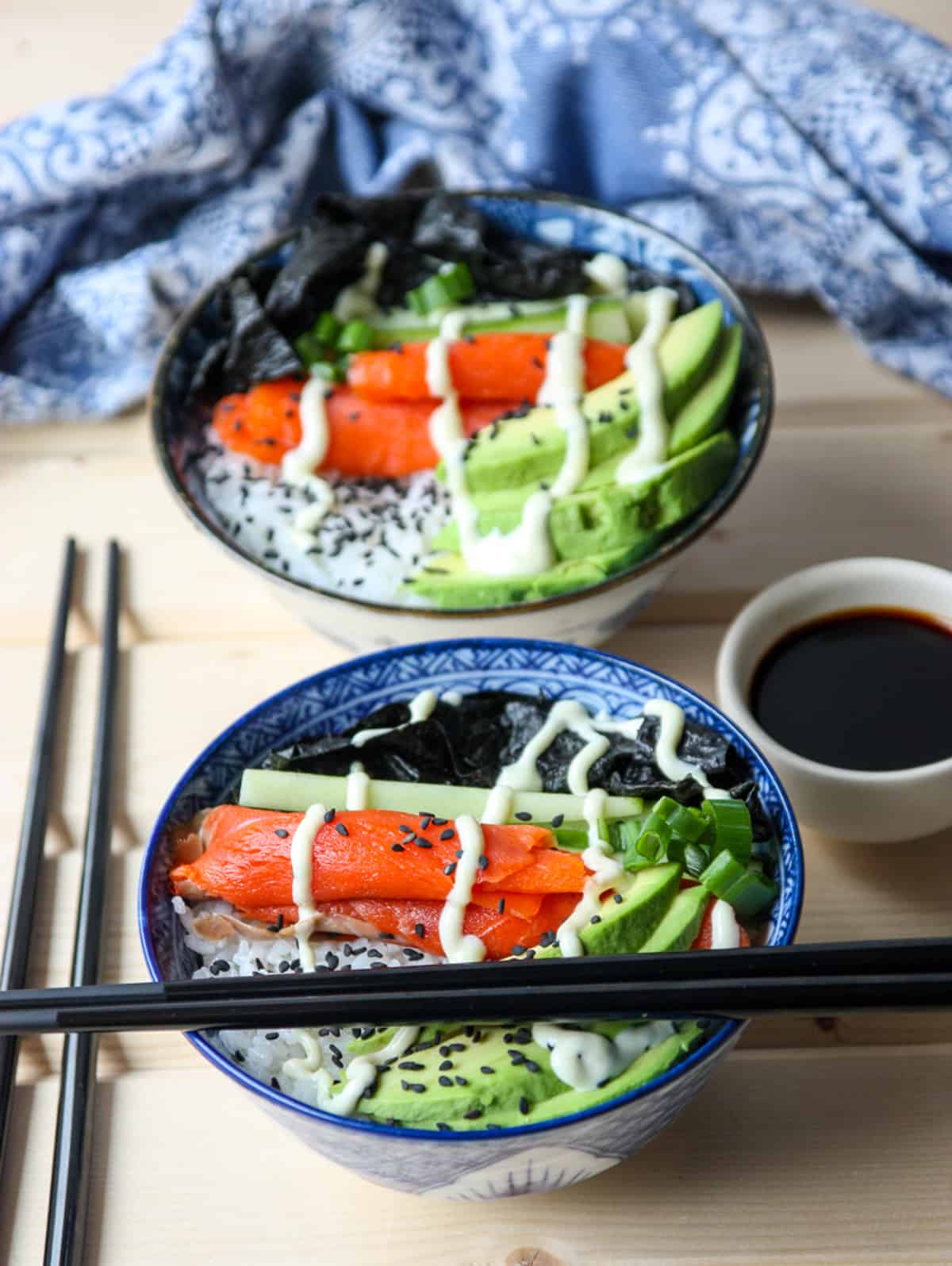 Two salmon sushi bowls with chopsticks.