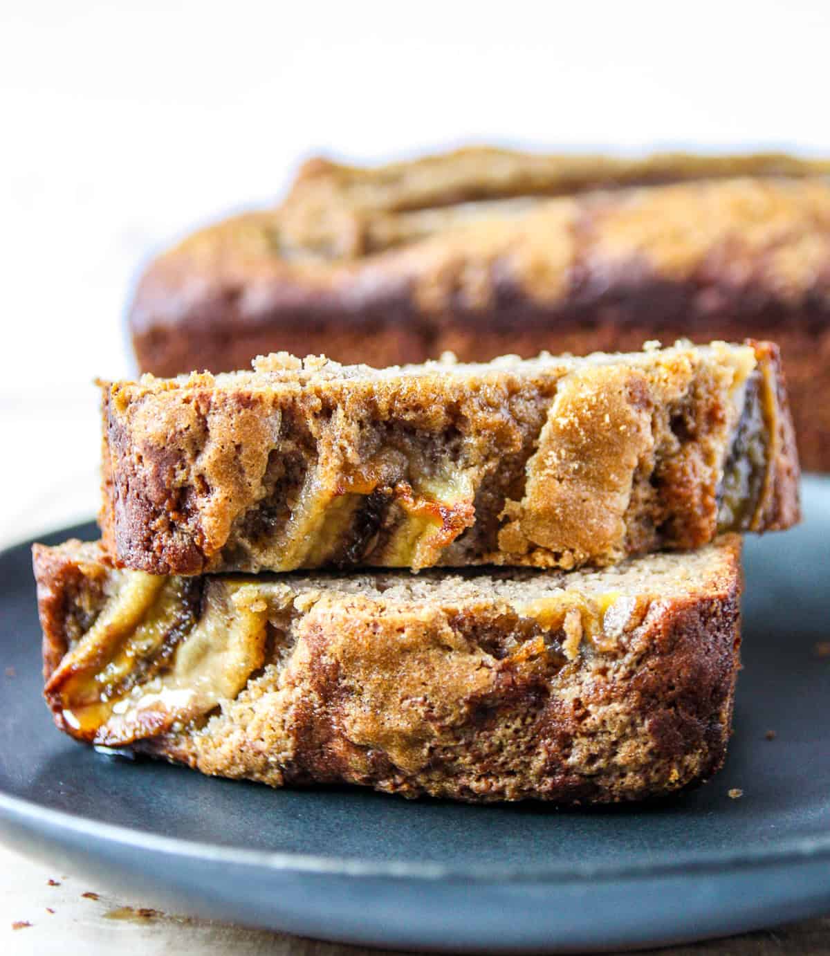 A stack of two slices of banana bread on a black plate.