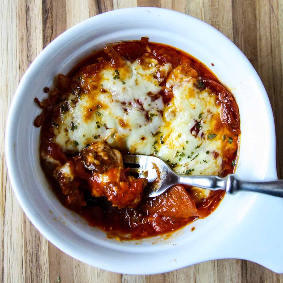 A baked pizza bowl with a fork inserted.