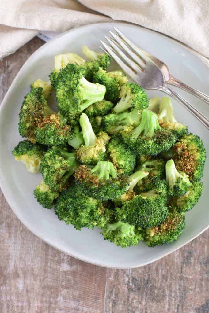 Air fried broccoli florets on a white plate.