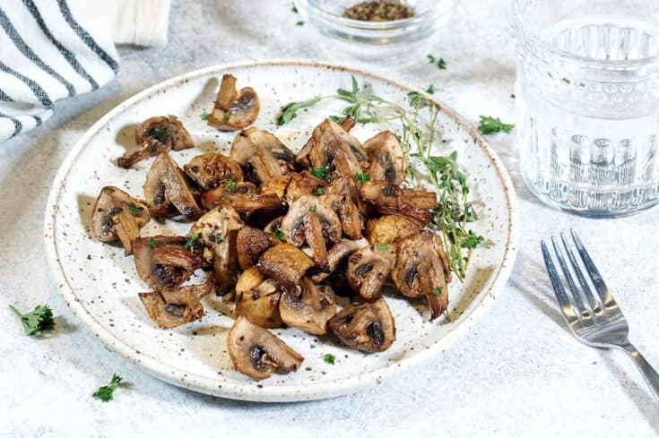 Air fried mushrooms on a speckled white plate.