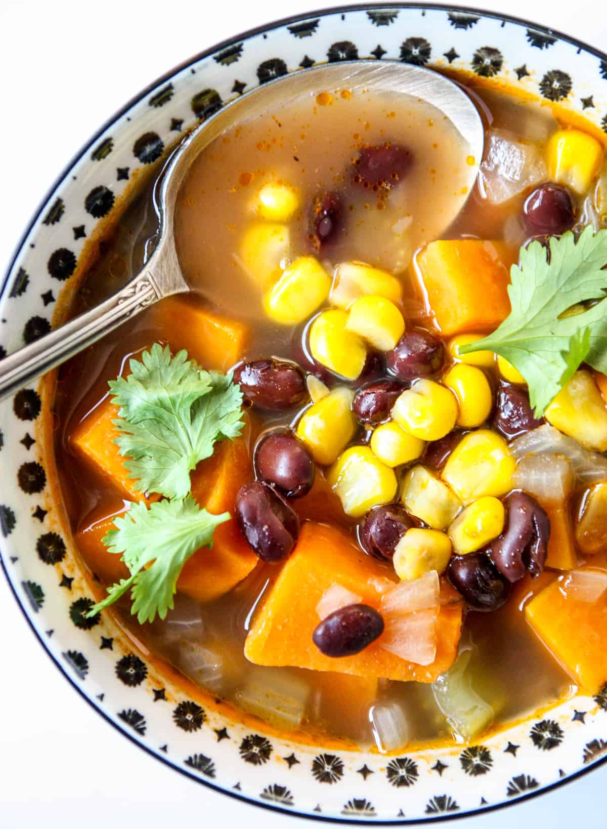 A bowl of black bean and sweet potato soup with a silver spoon.
