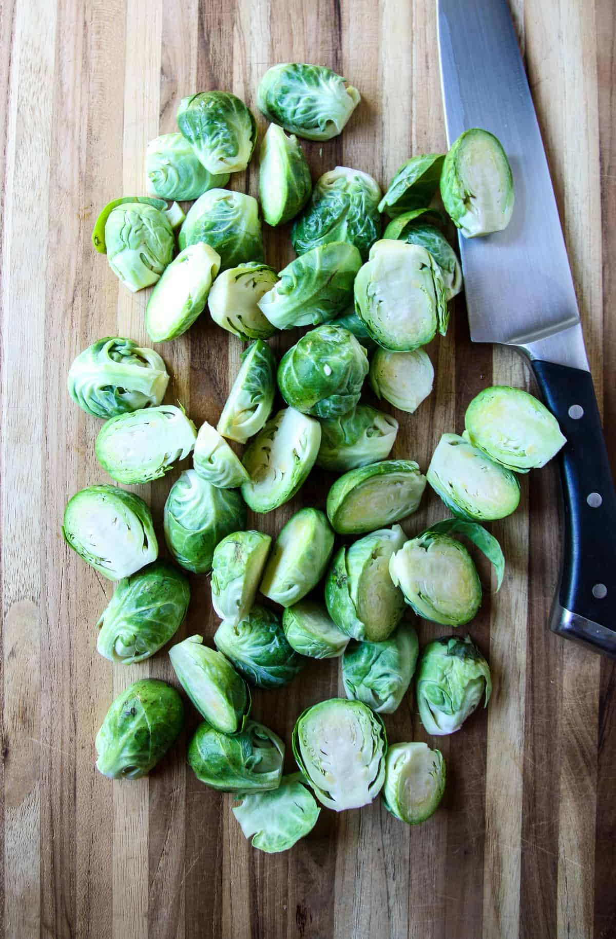 Brussels sprout halves on a wooden cutting board.