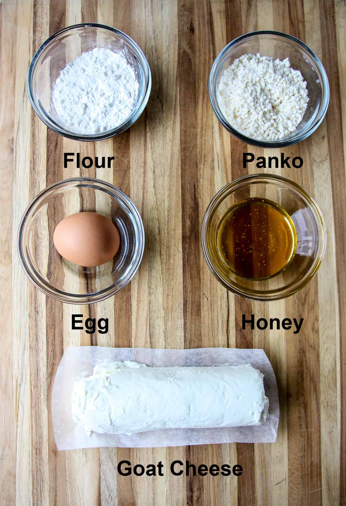 The ingredients to make air fried goat cheese balls, on a wooden board.