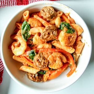 Cajun shrimp & sausage pasta in a white bowl.