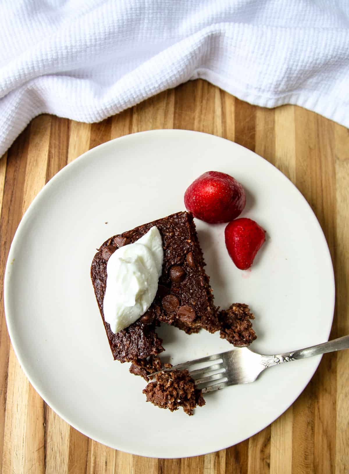 A serving of chocolate baked oats on a white plate with a silver fork.