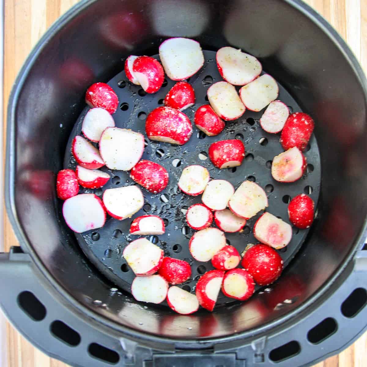 Seasoned radish slices in the air fryer basket ready to be cooked.
