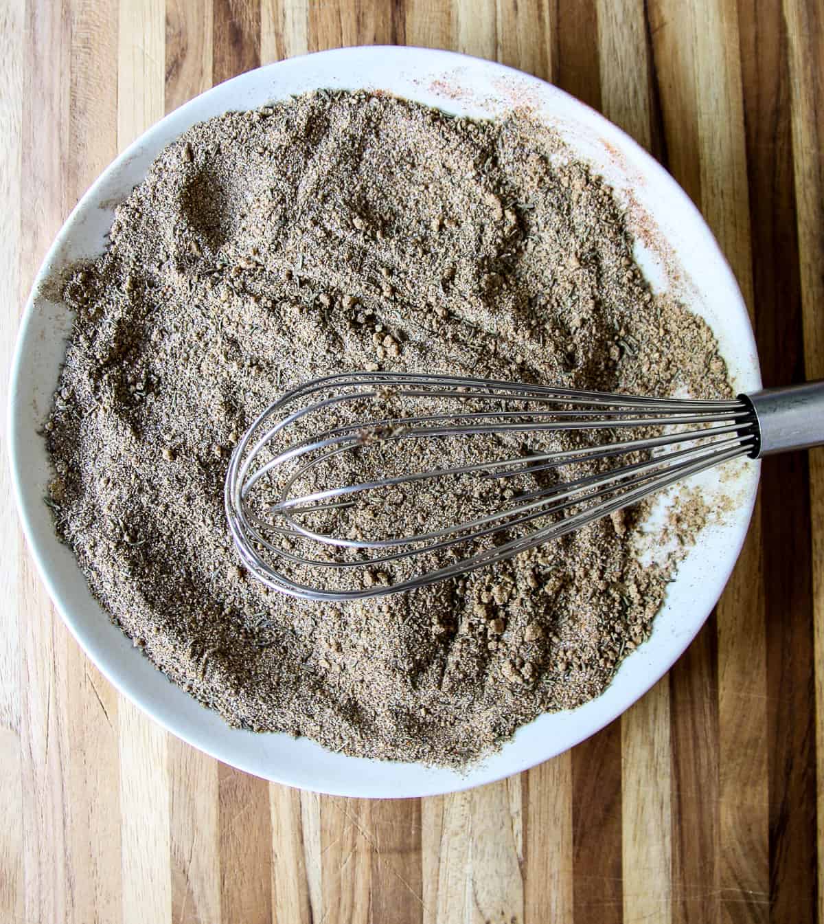 The spices being whisked together in a white bowl.
