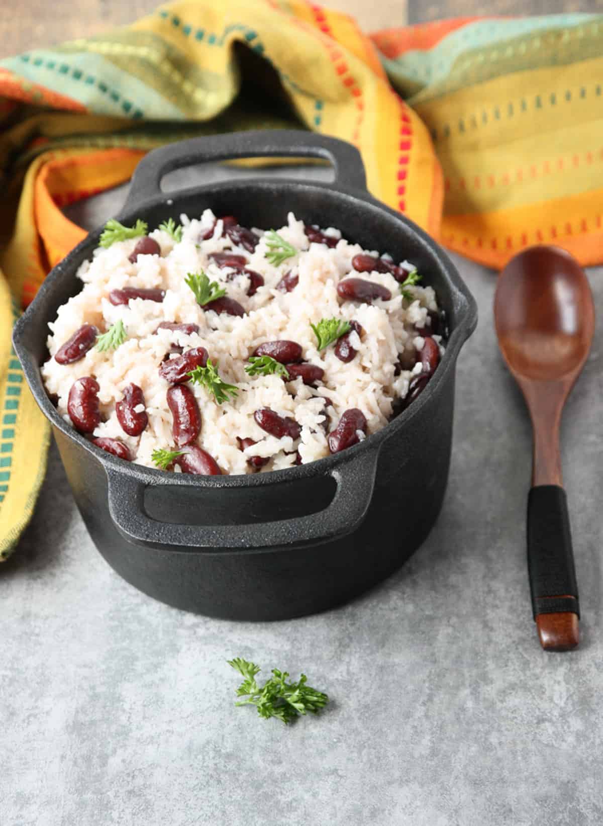A pot of coconut rice and peas on a countertop next to a multi colored linen napkin.