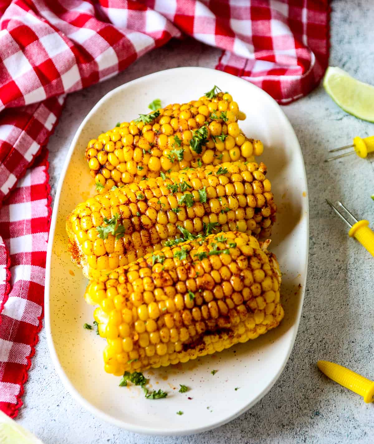Three peices of Cajun corn on the cob on a white plate.
