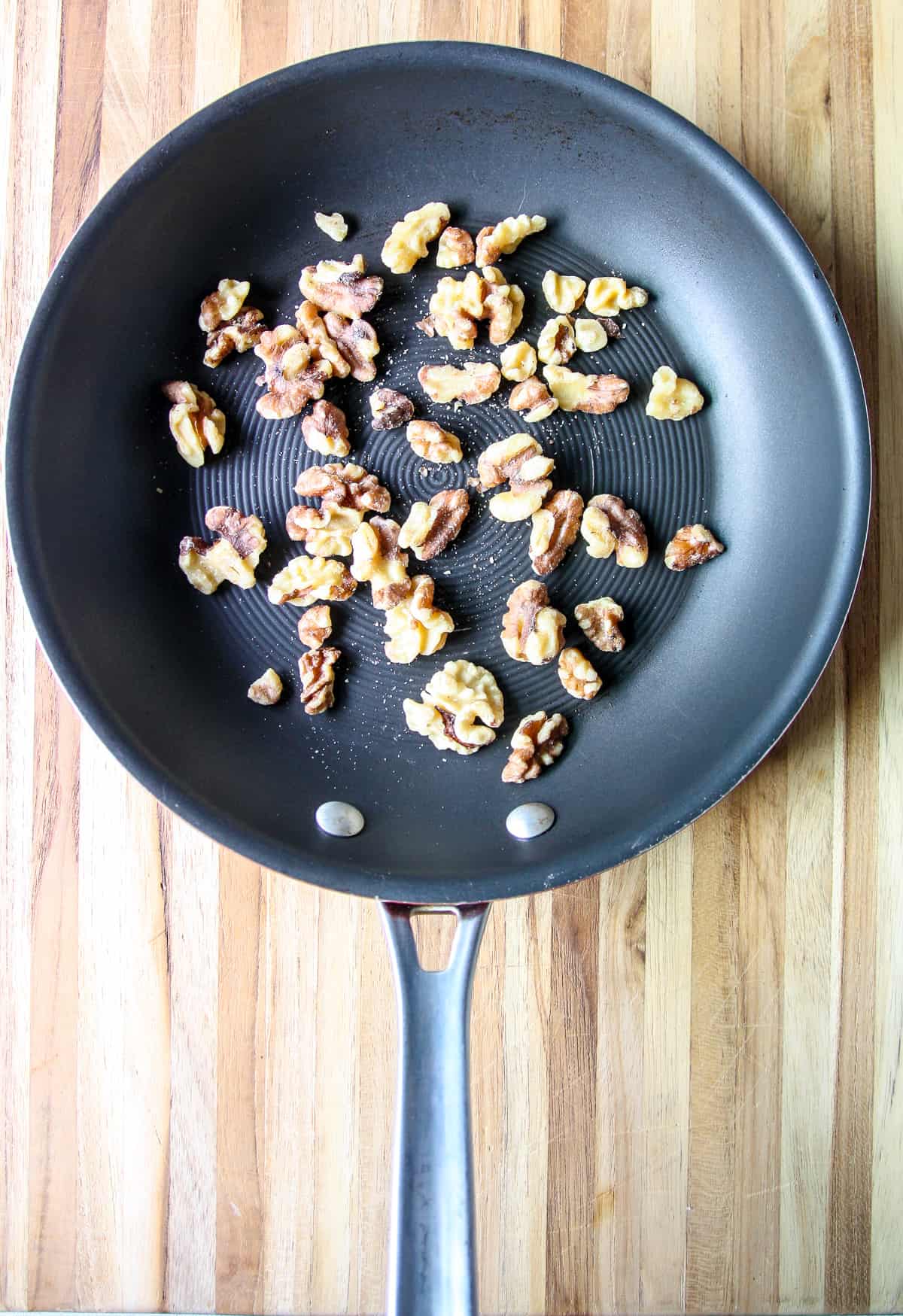 Walnut pieces toasting in a skillet.
