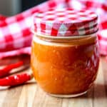 Cayenne pepper sauce in a glass jar with a red and white lid.