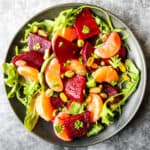 Beet and orange salad on a black plate.